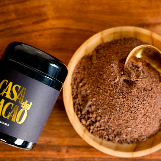 Casa del Cacao container and wooden bowl with grated cacao on a wooden surface