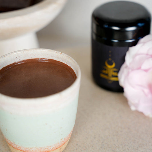 Ceramic cup with cacao next to a jar on a light surface